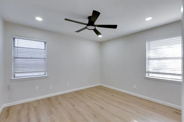 a view of empty room with wooden floor and fan