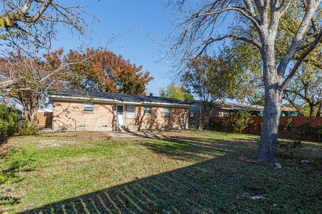 a view of a yard with plants and large trees