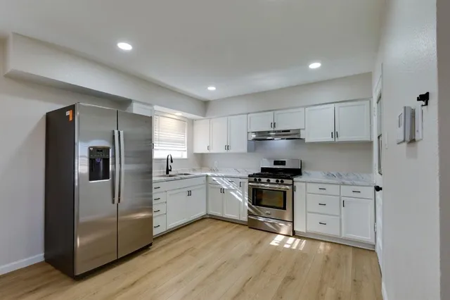 a kitchen with stainless steel appliances granite countertop a stove a refrigerator and a sink