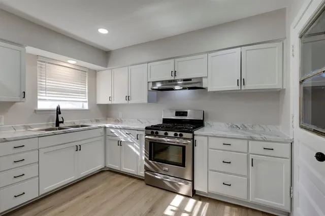 a kitchen with white cabinets stainless steel appliances and sink