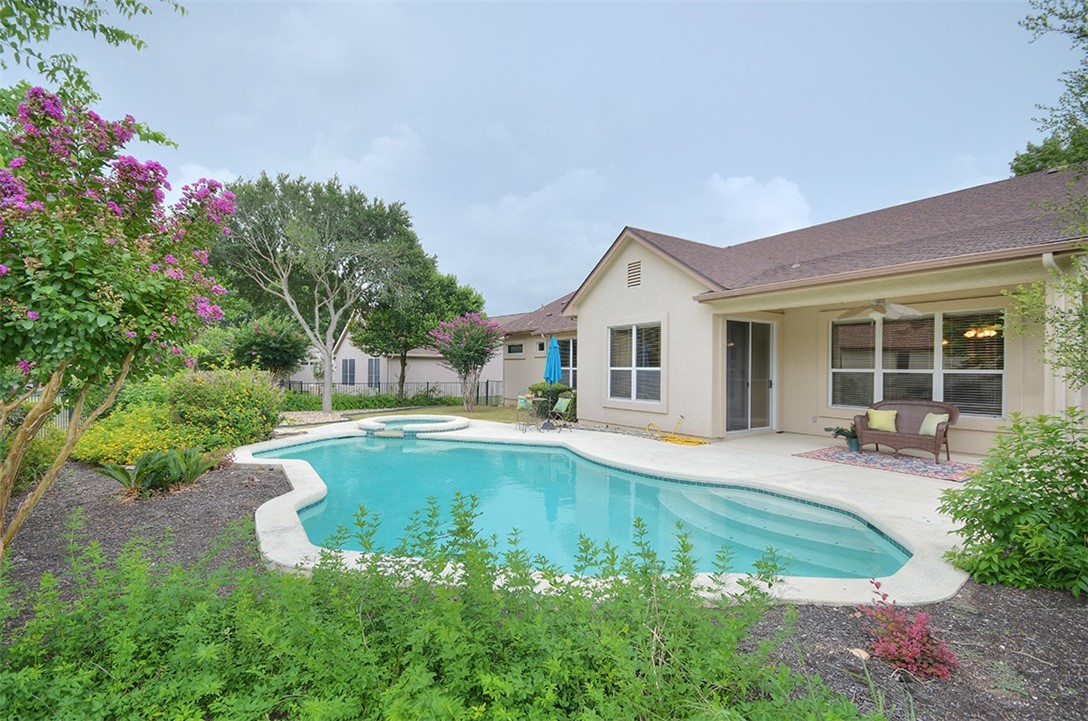 a view of pool with lawn chairs and plants