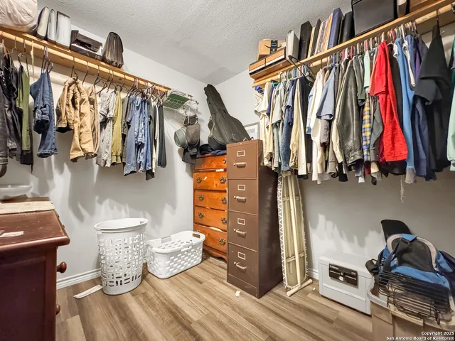 a walk in closet with wooden floor