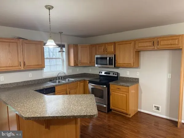 a kitchen with granite countertop a sink a counter space appliances and cabinets
