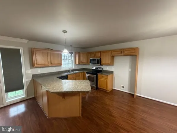 a kitchen with stainless steel appliances granite countertop a sink a stove and a wooden floors