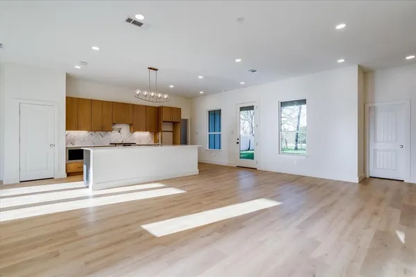 a view of an empty room with window and wooden floor