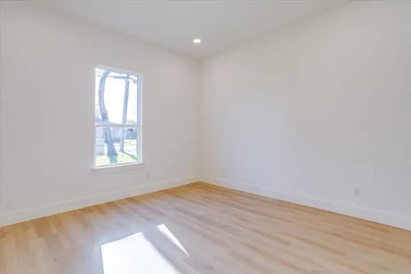 a view of an empty room with window and wooden floor