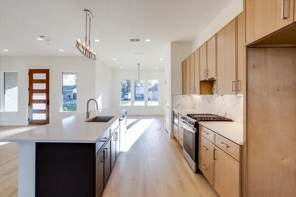 a kitchen with stainless steel appliances granite countertop a sink dishwasher a stove and a wooden floor
