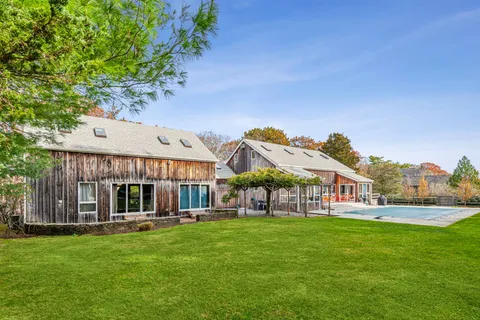 an aerial view of a house with swimming pool and large trees