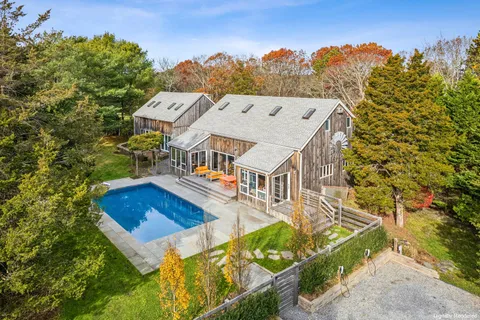 a view of a big house with a big yard plants and large trees
