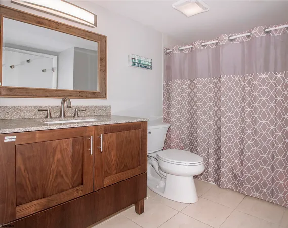 a bathroom with a granite countertop toilet sink and mirror