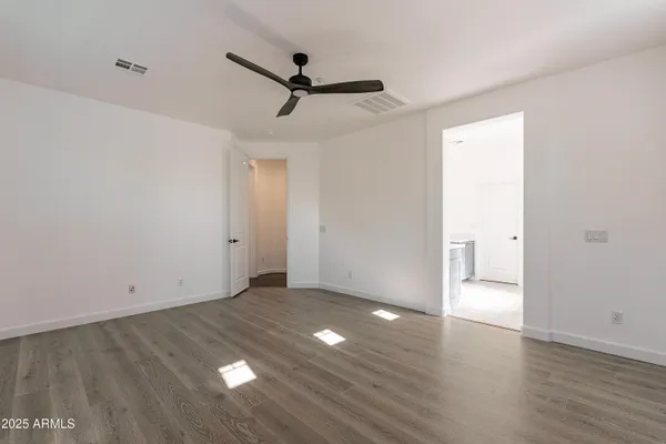 a view of empty room with wooden floor and fan