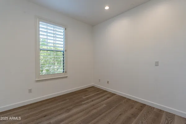 a view of an empty room with wooden floor and a bathroom