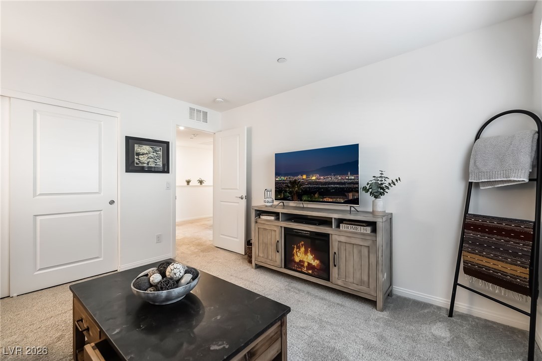 12235 Glass Desert Road, Unit 2 Las Vegas, NV 89183 - Photo 25 of 33 Living room with light colored carpet and a lit fireplace