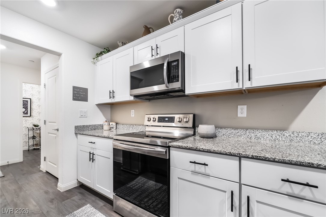 12235 Glass Desert Road, Unit 2 Las Vegas, NV 89183 - Photo 4 of 33 Kitchen featuring appliances with stainless steel finishes, white cabinets, light stone counters, and dark wood finished floors