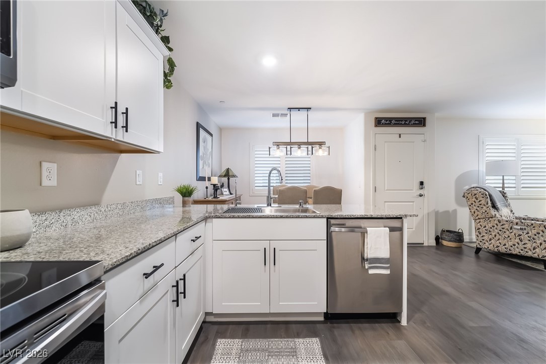 12235 Glass Desert Road, Unit 2 Las Vegas, NV 89183 - Photo 5 of 33 Kitchen with white cabinetry, a peninsula, appliances with stainless steel finishes, and light stone counters