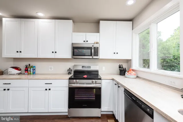 a kitchen with cabinets appliances a sink and a window