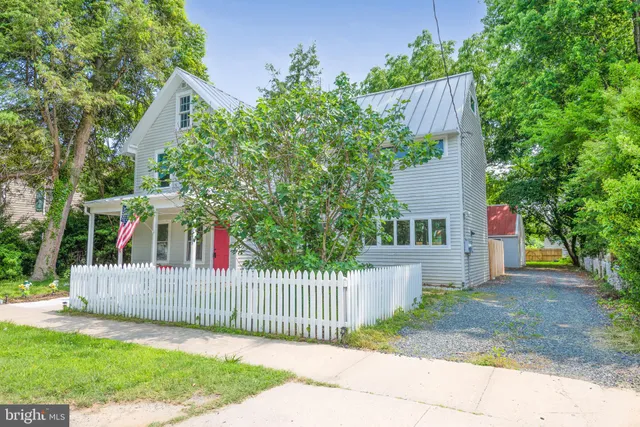 front view of a house with a small yard and a large tree