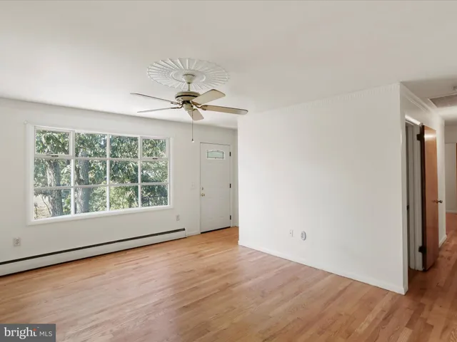 a view of an empty room with a window and wooden floor