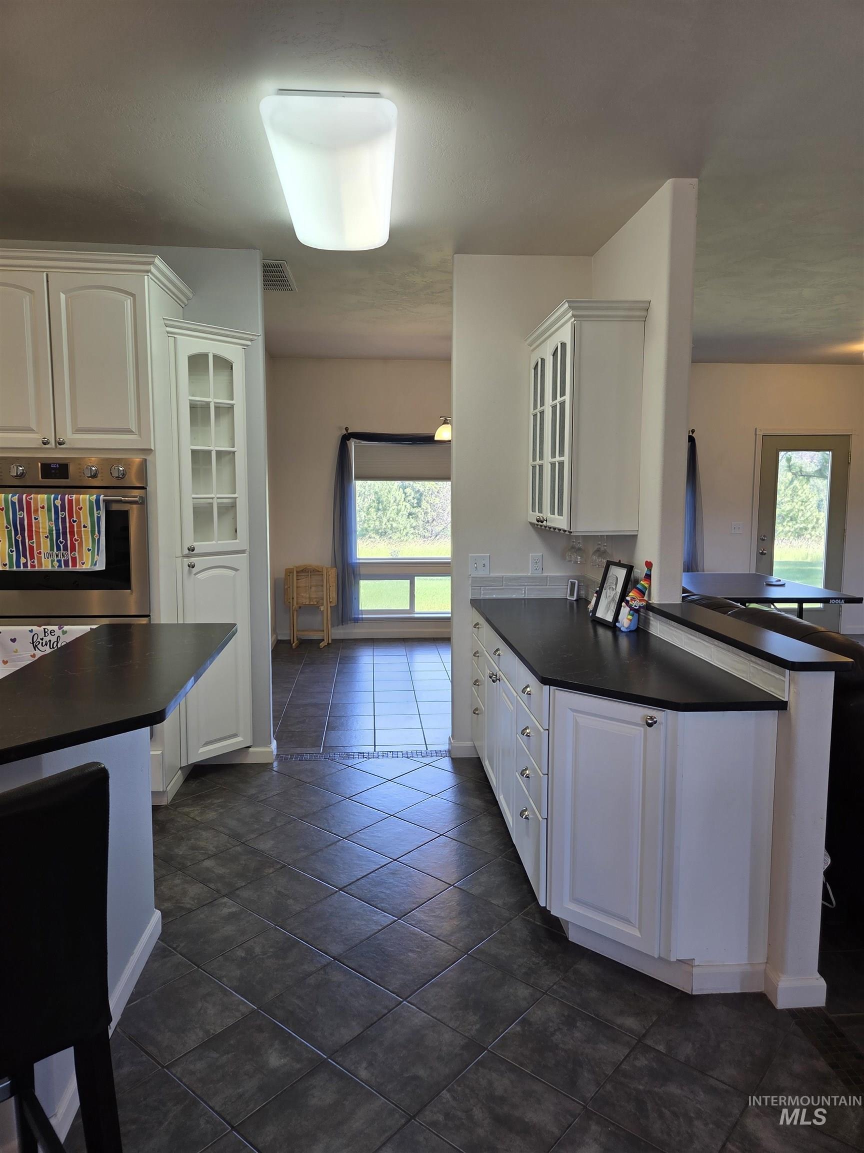 1085 Wallen Road Moscow, ID 83843 - Photo 12 of 50 Kitchen featuring white cabinetry with brushed nickel hardware, dark countertops, built-in stainless steel oven, and diagonal tile flooring