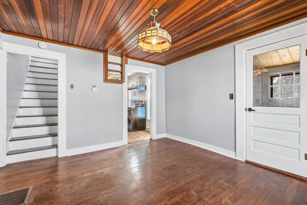 an empty room with wooden floor closet and windows