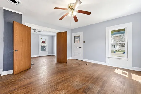 a view of an empty room with window and wooden floor