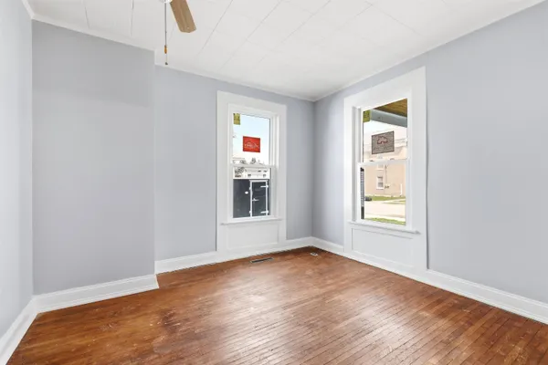 an empty room with wooden floor and windows