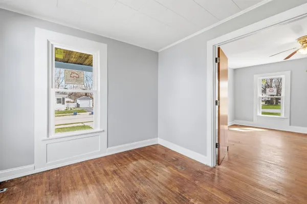 a view of an empty room with window and wooden floor