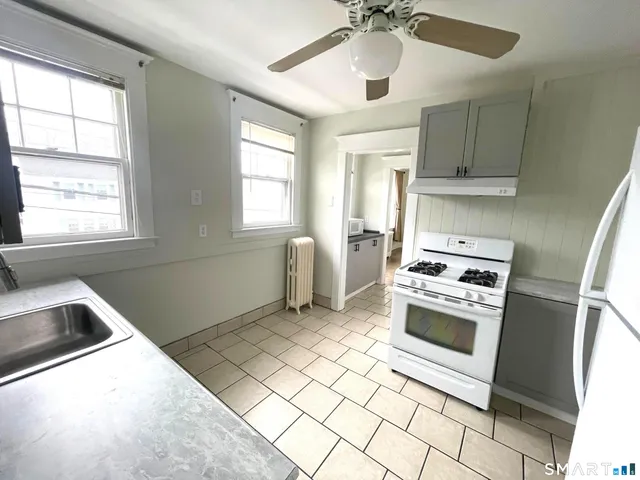 a kitchen with stainless steel appliances granite countertop a sink a stove a refrigerator cabinets and a window