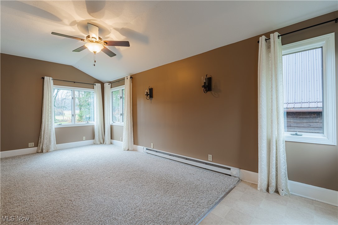 2990 Randolph Road Mogadore, OH 44260 - Photo 14 of 28 Spare room featuring light carpet, vaulted ceiling, baseboard heating, and ceiling fan