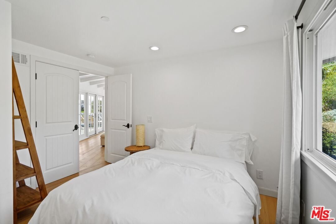 30081 Harvester Road Malibu, CA 90265 - Photo 25 of 33 a bedroom with a bed and a large mirror next to a window