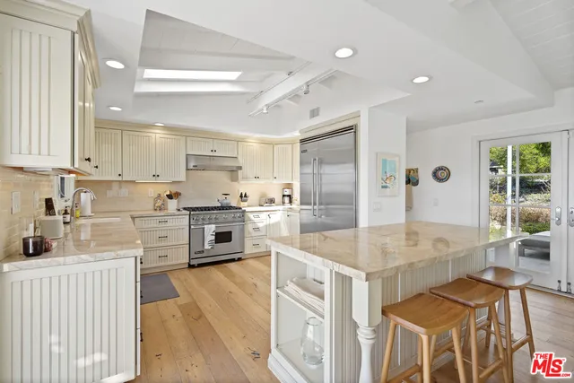 a kitchen with stainless steel appliances granite countertop a stove top oven a sink dishwasher a dining table and chairs with wooden floor