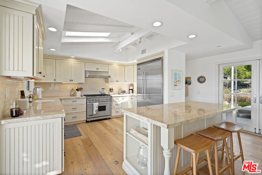 30081 Harvester Road Malibu, CA 90265 - Photo 7 of 33 a kitchen with stainless steel appliances granite countertop a stove top oven a sink dishwasher a dining table and chairs with wooden floor