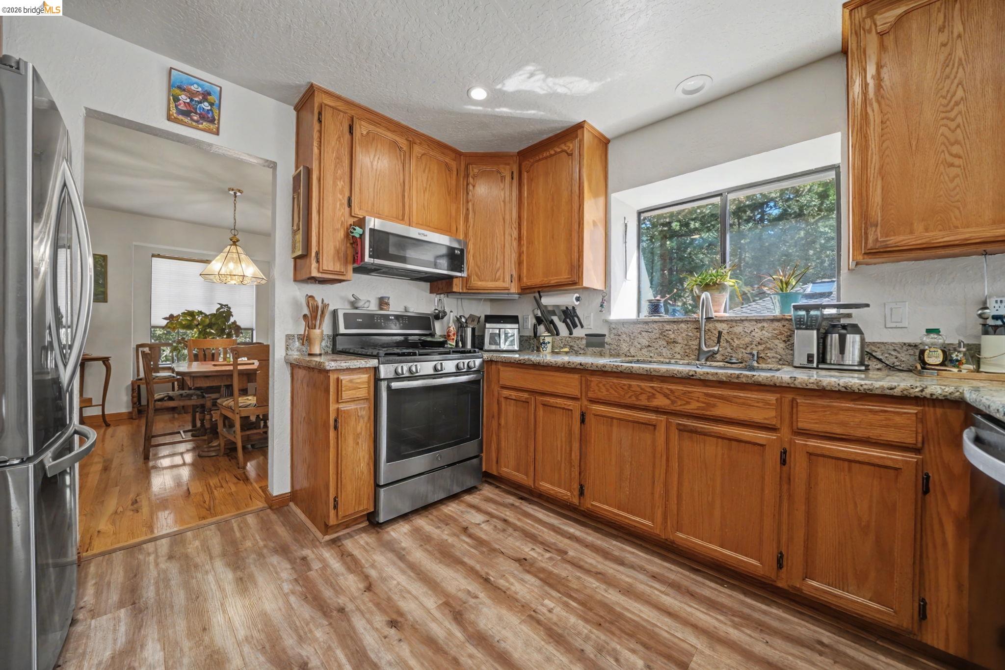 1554 Vine Maple Drive Murphys, CA 95247 - Photo 13 of 54 a kitchen with stainless steel appliances granite countertop a stove a sink dishwasher a microwave oven with cabinets and wooden floor