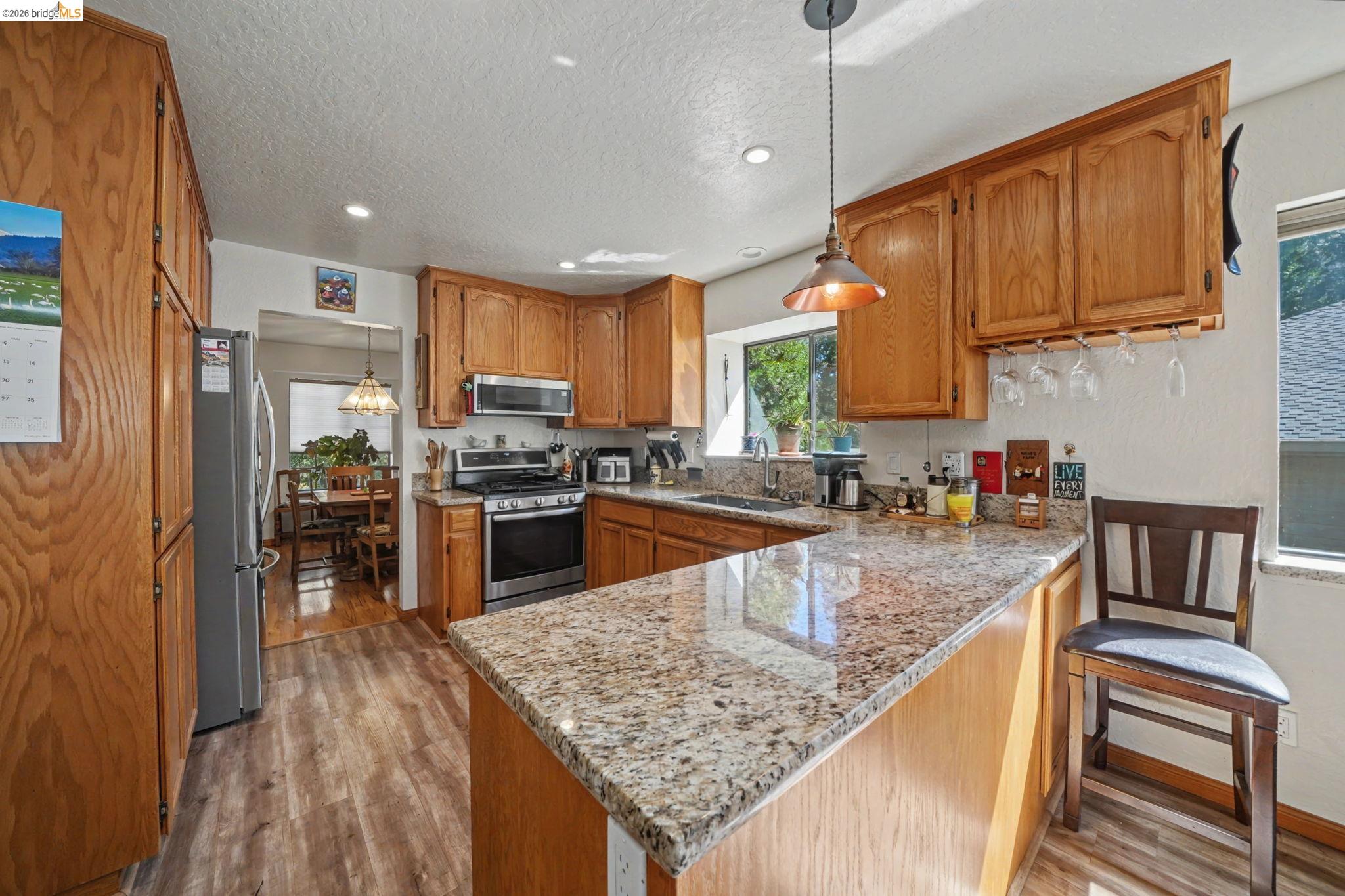 1554 Vine Maple Drive Murphys, CA 95247 - Photo 14 of 54 a kitchen with granite countertop wooden cabinets a sink a stove and stainless steel appliances