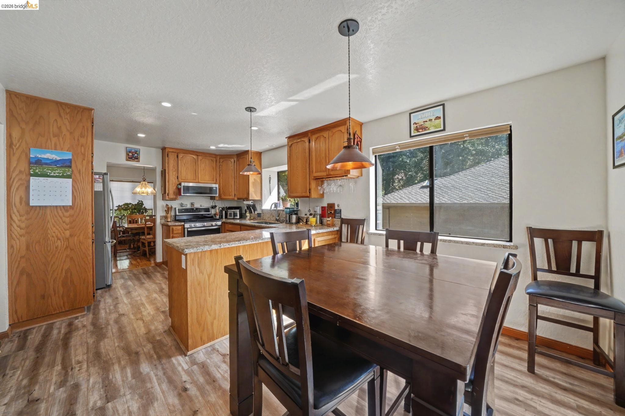 1554 Vine Maple Drive Murphys, CA 95247 - Photo 18 of 54 a dining room with stainless steel appliances granite countertop a table chairs and a wooden floor
