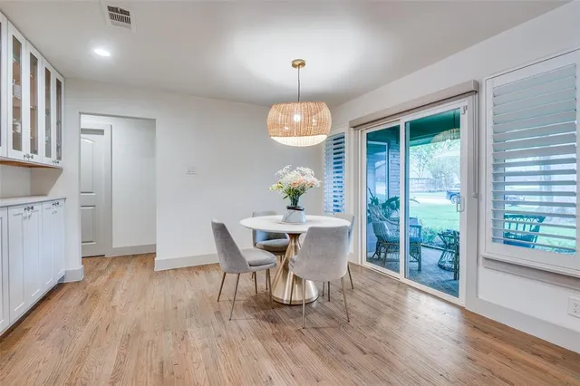 a dining room with wooden floor a chandelier a glass table and chairs