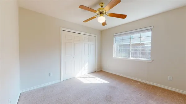 an empty room with windows and fan