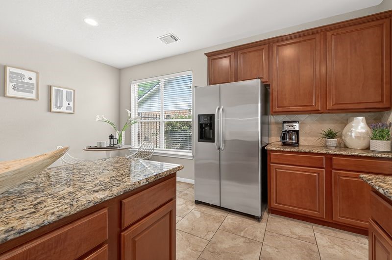 111 South Rocky Point Circle Spring, TX 77389 - Photo 16 of 41 a kitchen with granite countertop stainless steel appliances a refrigerator and wooden cabinets