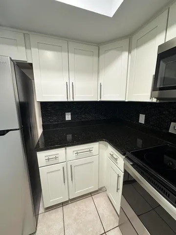 a kitchen with granite countertop white cabinets and black appliances