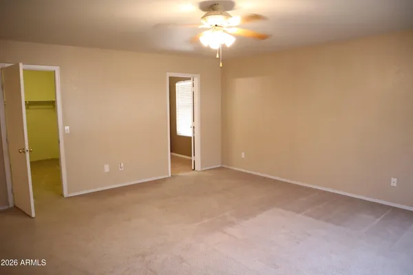 an empty room with a chandelier fan and windows