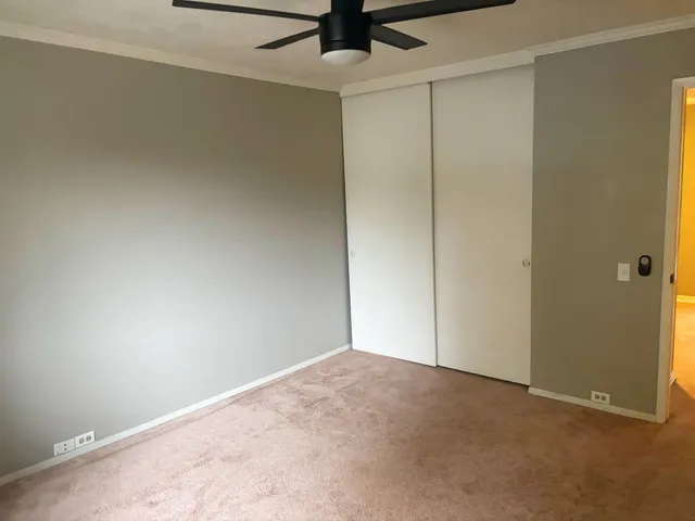 an empty room with a ceiling fan and carpet