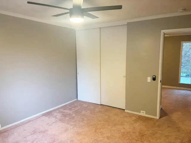 an empty room with closet and a chandelier fan