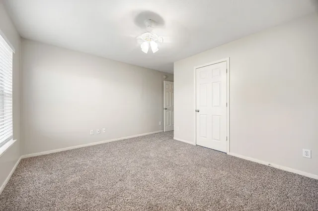 an empty room with a chandelier fan and windows