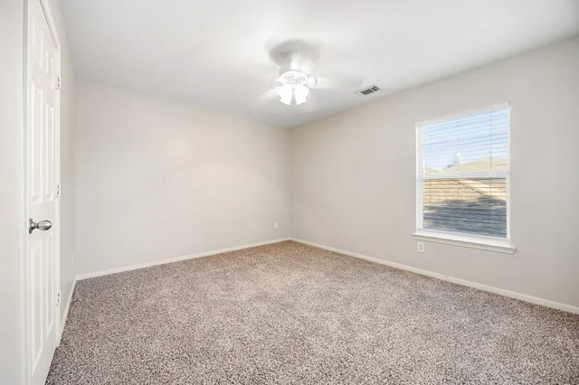 an empty room with a chandelier fan and window