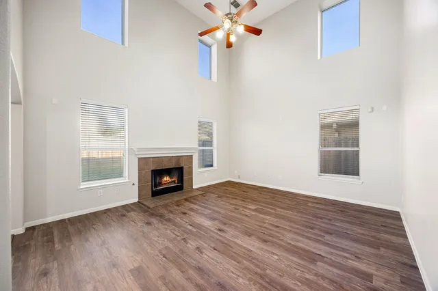 a view of an empty room with wooden floor fireplace and a window
