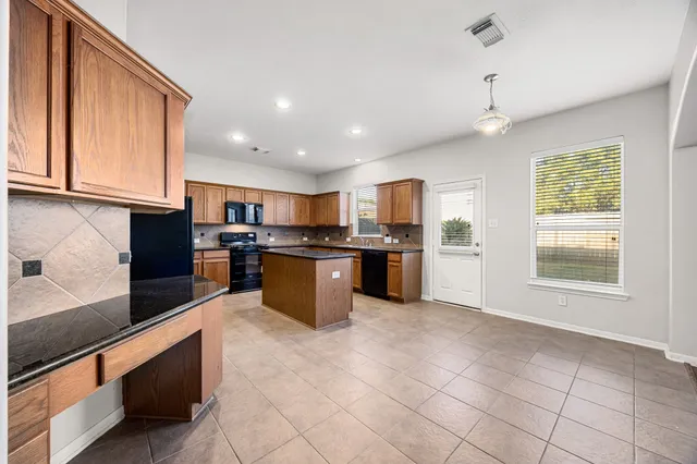 a kitchen with stainless steel appliances granite countertop a stove top oven a sink a counter top space cabinets and a window