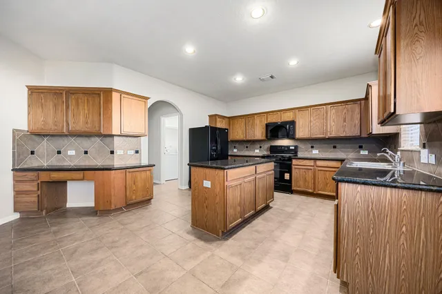 a large kitchen with stainless steel appliances granite countertop a stove a sink dishwasher a microwave oven and a refrigerator