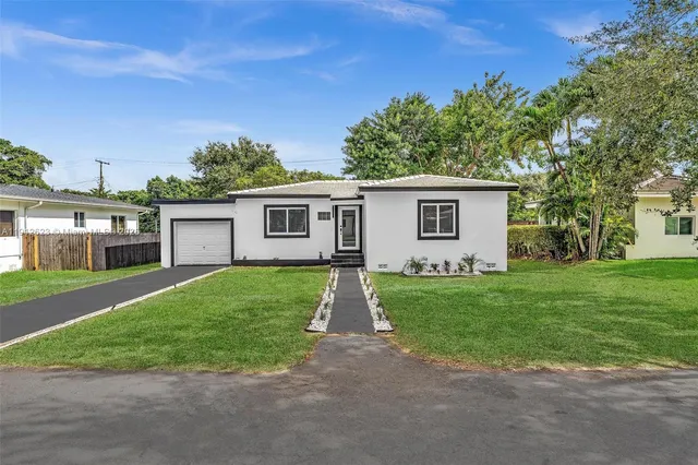 a view of a yard in front of a house with plants and large tree