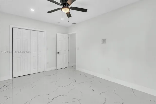 an empty room with a ceiling fan and carpet