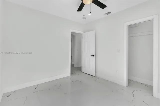 an empty room with a ceiling fan and carpet